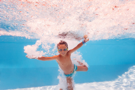 可爱的小男孩在游泳池里溅水后跳，做泡泡