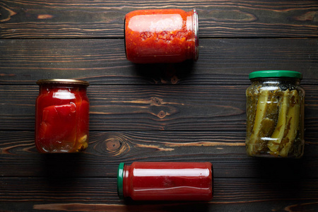 Preserved vegetables in jars, ont a dark background. Cucumbers, 