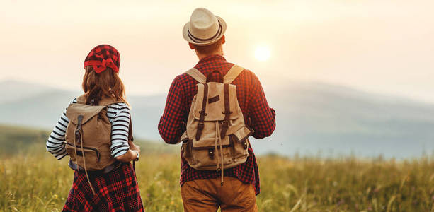 happy couple man and woman tourist at top of mountain at sunset 