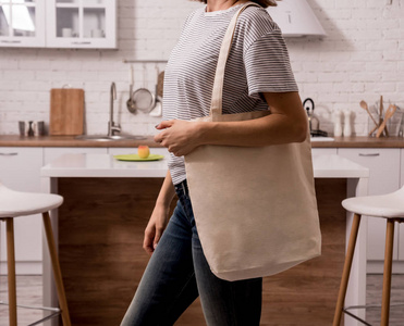 Young girl holding a cloth bag. At the kitchen. I am not plastic