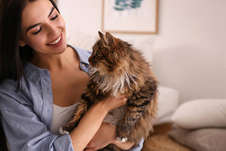 漂亮的年轻女人和她可爱的猫在卧室里。毛绒宠物