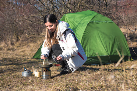 兴高采烈的女人独自在帐篷前露营做饭