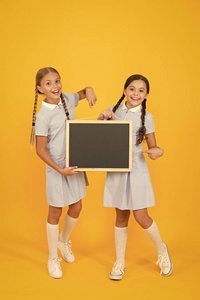 学校新闻。真实的信息。小女孩拿着黄色背景的书写面。儿童和书写信息的黑板。信息空白板。新鲜学校信息复制空间
