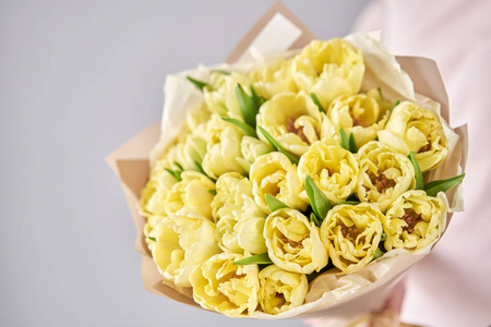 女人手上的黄色淡色郁金香。年轻漂亮的女人拿着春天的花束。一束刚剪下的春花在女性手中