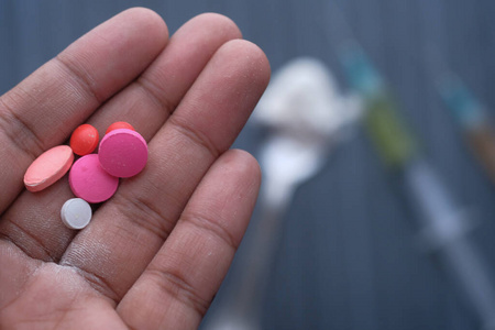 top view of pills on man hand and syringe on table 