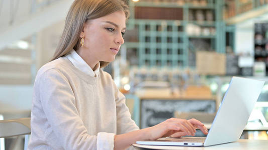 在咖啡馆里用笔记本电脑工作的年轻女人