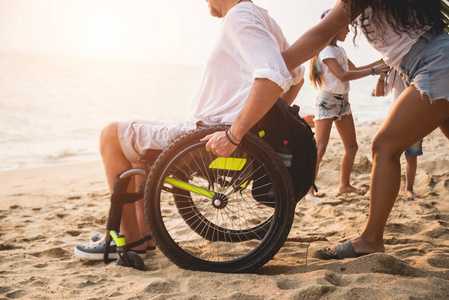 残疾人坐在轮椅上，妻子在沙滩上。