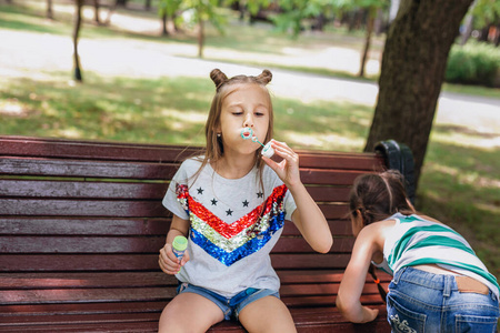 年轻时髦的女孩在夏日公园吹肥皂泡。