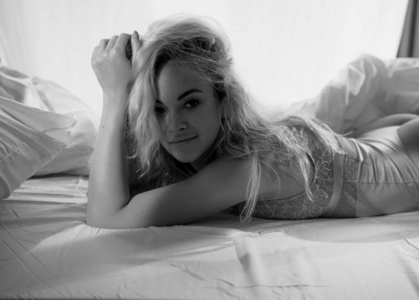 性感而健康的女人躺在床上，穿着蕾丝内衣，看起来很诱人。黑白照片