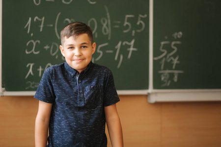 可爱的男孩站在教室黑板的背景上。教育。小学