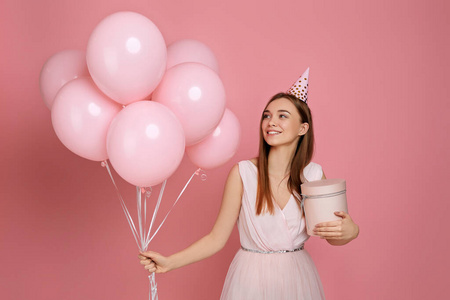 戴着生日帽的女人用粉红色的气球庆祝
