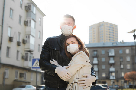 一男一女在自家院子里，戴着口罩，拥抱着。冠状病毒。科维德19。