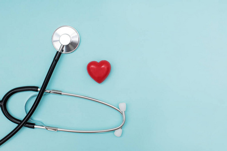 医用听诊器和小型装饰心脏隔离在蓝色背景上。