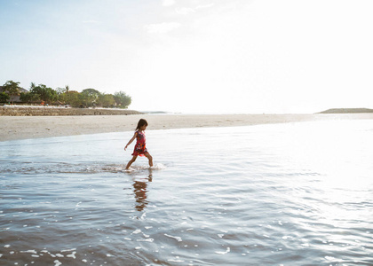 小女孩一边玩水一边在沙滩上跑