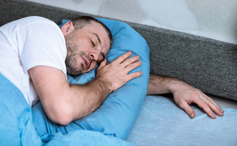男人睡在床上抱着枕头呆在家里图片