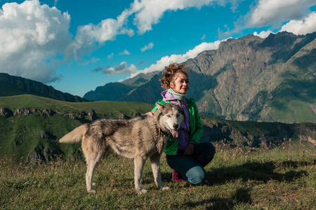 年轻女子与爱犬哈士奇一起在山顶欣赏山景