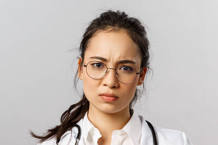 医疗医学和药学概念。担心的亚洲女医生的画像，皱眉不安，大拇指朝下拿着坏药，建议不要自我治疗病毒，请联系你的治疗师