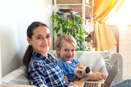 远程教育在线教育和工作。孩子在家里远程学习坐在沙发上。使用移动笔记本电脑