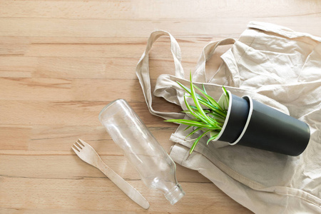 环保型有机一次性厨房用具，玻璃瓶，袋子和纸杯，木质背景植物。生态循环利用零浪费无塑料概念。俯视图