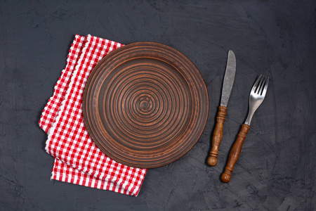 Empty plate and napkin on black background