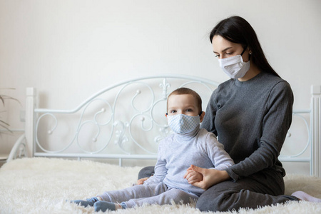 戴着医用防护面具的小男孩。母亲给婴儿戴上无菌医用口罩。孩子，戴着面罩