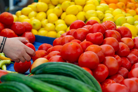 一位妇女在街市上用塑料袋挑选西红柿。购买新鲜的有机水果和蔬菜