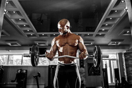 肌肉发达的男子在健身房锻炼，肱二头肌上有哑铃，强壮的男性躯干腹肌