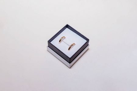 盒子里有金色的结婚戒指。白色隔离金戒指背景。漂亮闪亮的订婚戒指，镶在黑色丝绒盒子里。情人节求婚礼物。复制空间。