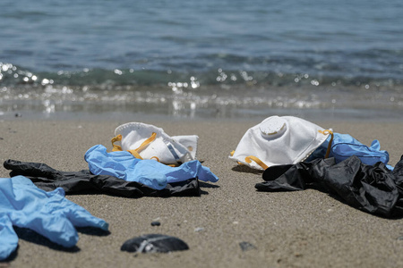 Protective virus mask and plastic gloves garbage trash on sandy 