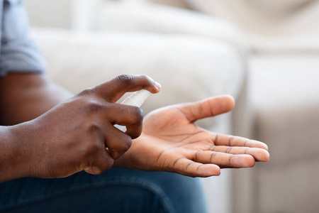 美国黑人男子在家里给手喷洒抗菌消毒剂