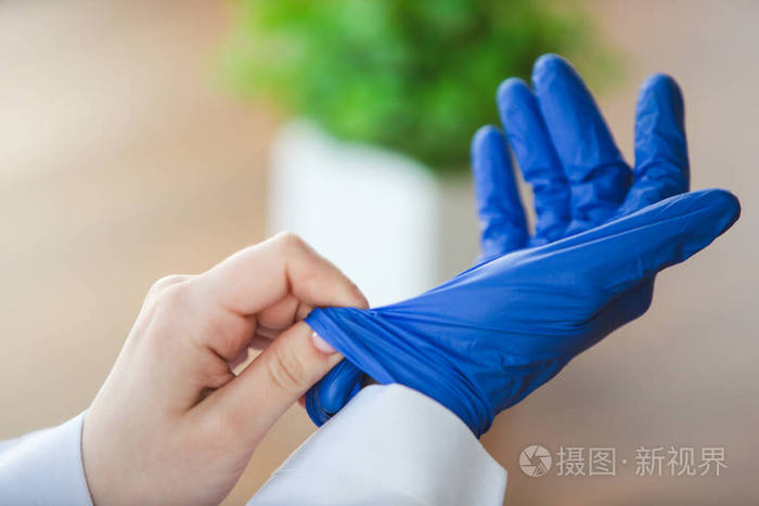 医生手戴蓝色防护手套的木桌背景特写镜头