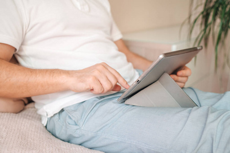  man in pajamas uses tablet at home in bed