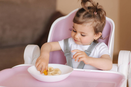 快乐的小女孩坐在高椅子上吃异国水果的画像。儿童健康营养