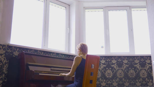 优雅脆弱的女人在客厅的家里弹钢琴