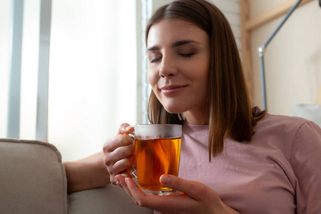 女士在家里闭着眼睛闻着茶香图片