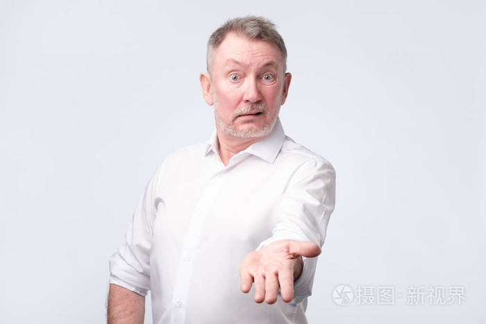 一个穿着白衬衫的愤怒的老人看着摄像机指责