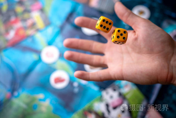 手在操场上掷黄色骰子幸运和兴奋棋盘游戏的概念动态游戏时刻