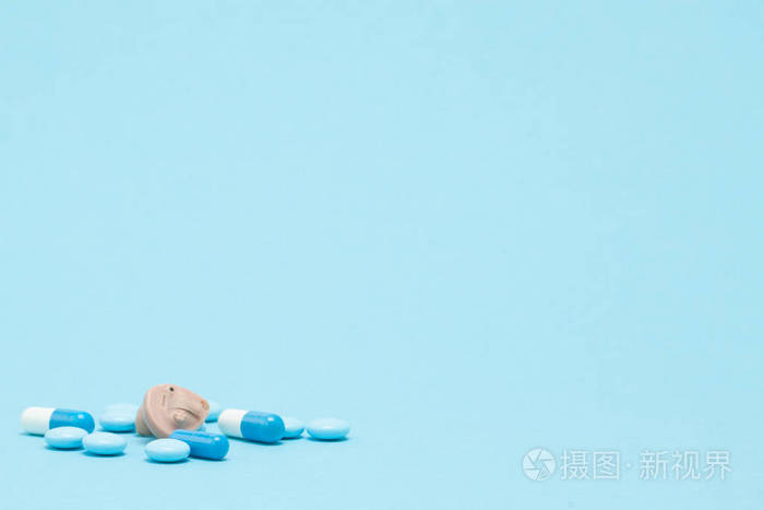 蓝色背景的助听器和蓝色药丸.医学,药学
