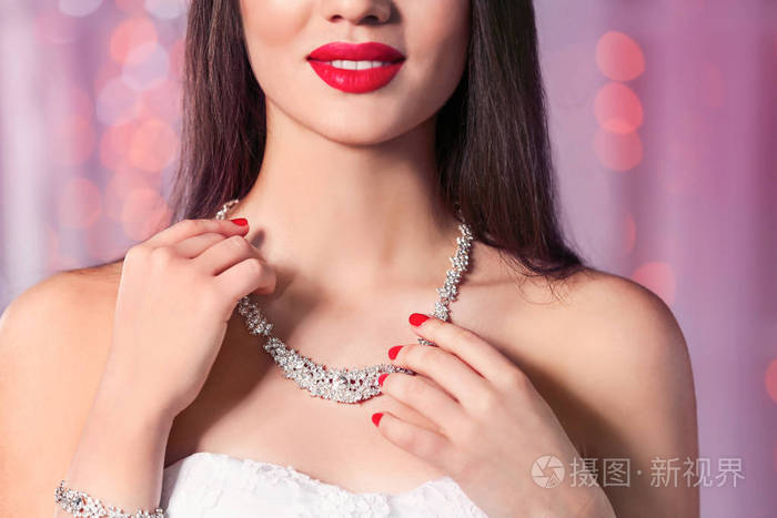 美女戴着时髦的珠宝对着模糊的灯光特写