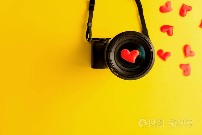 平放无镜照相机带镜头黄色背景上有爱心红心订婚或新婚
