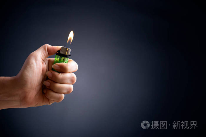 在黑暗的背景下,女人手拿着点燃的打火机.