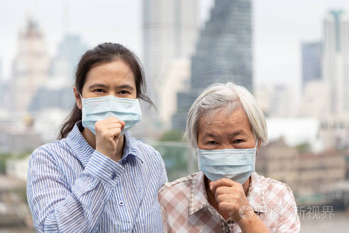 亚洲妇女或母女咳嗽戴口罩防护老年人和成年妇女因城市空气污染戴口罩