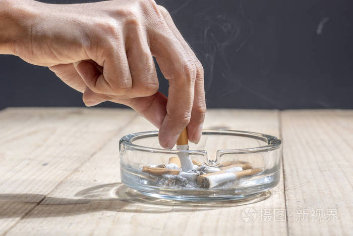 用手在透明烟灰缸里掐灭香烟