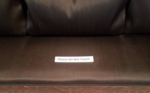 请勿触摸棕色织物沙发上的标牌图片