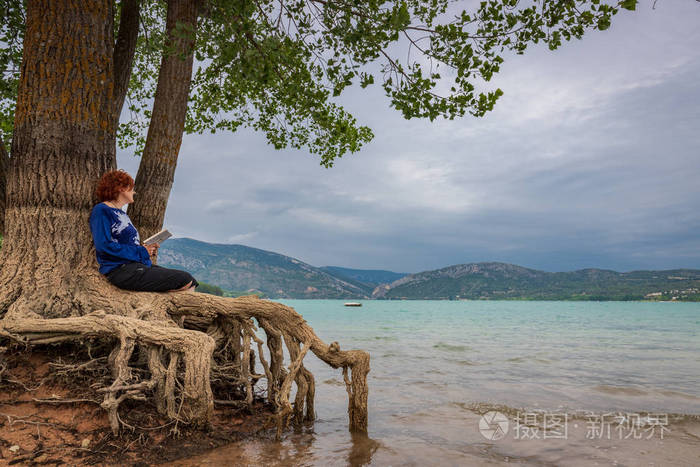 坐在湖边的树上看书的女人照片-正版商用图片2mlqh4-摄图新视界