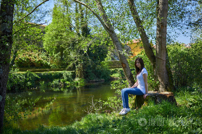 坐在阿拉里兹河边树桩上的年轻女子照片-正版商用图片2mski6-摄图新