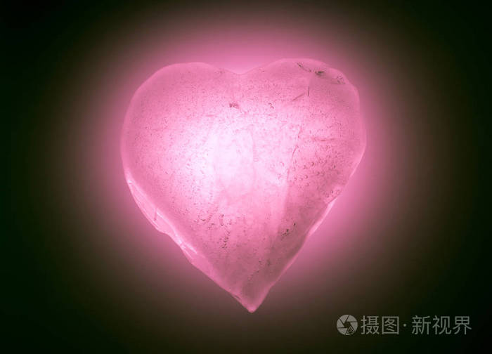 冰封的心象征柔和的粉红色特写镜头在黑暗中发光有气泡的冰的质地