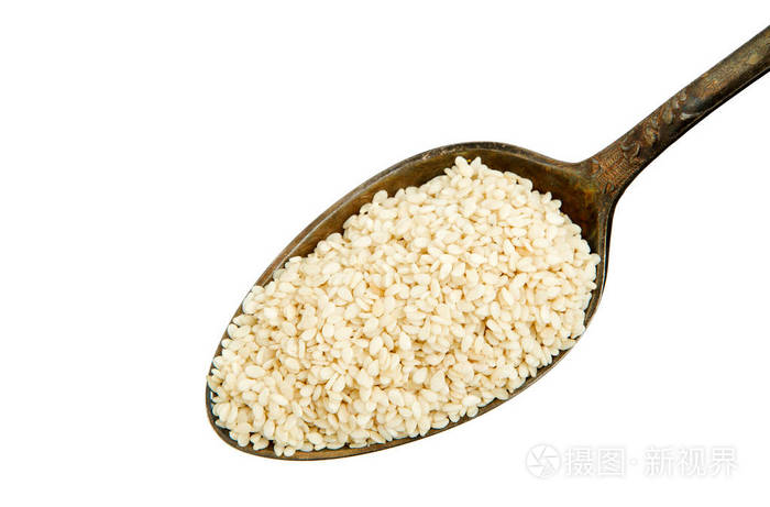 白色背景上隔离的勺子里的白芝麻单独调味从上面看