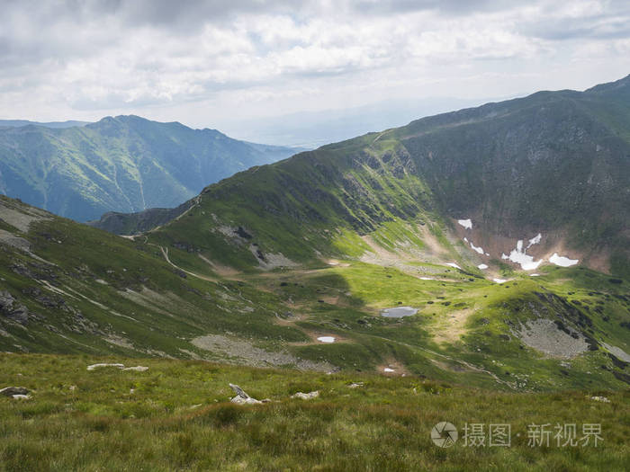 陡峭的绿色山峰和山脊上的徒步小径.夏日蓝天白云.