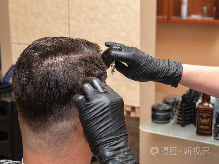发型师使用剪刀和梳子特写镜头造型师手戴黑色橡胶手套美发厅内部设计